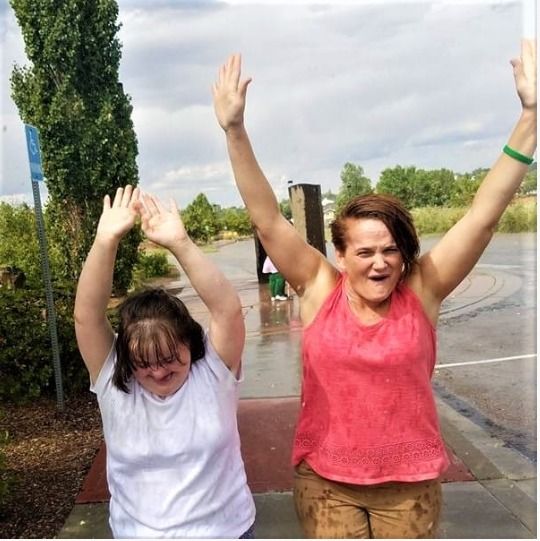 Two Elderhaus participants cheering with their arms in the air outdoors